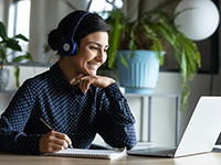 business woman wearing wireless headphones looking at laptop screen, reading listening online courses 